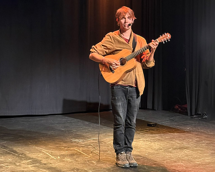 Merijn speelt gitaar tijdens lezing psychologie van een-gelukkig leven